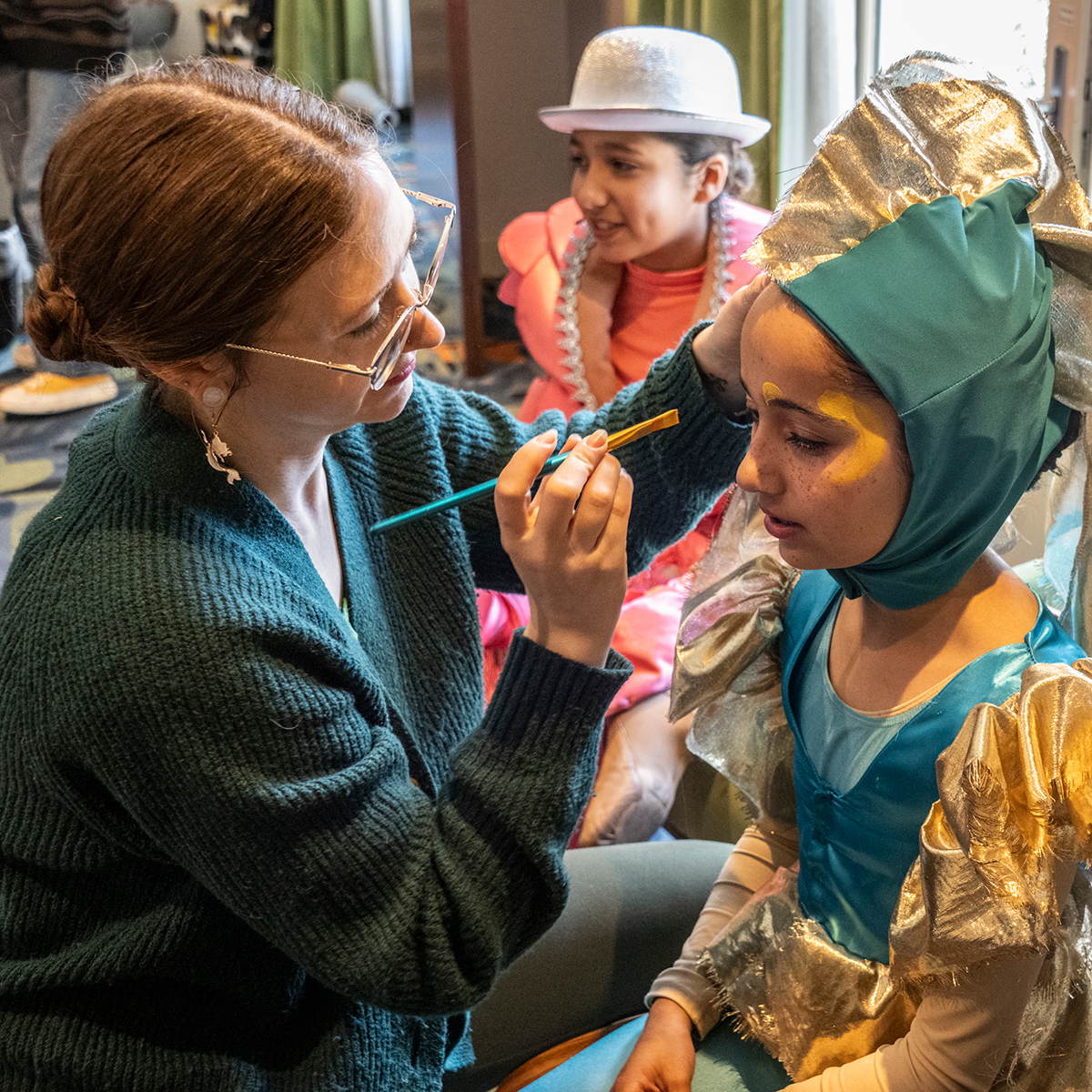 Woman applying stage make-up on a child